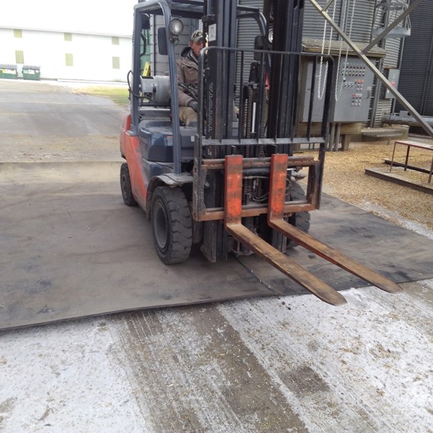Forklift driving over grain pit cover
